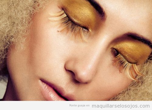 Maquillaje de ojos dorado y con plumas que simula el sol
